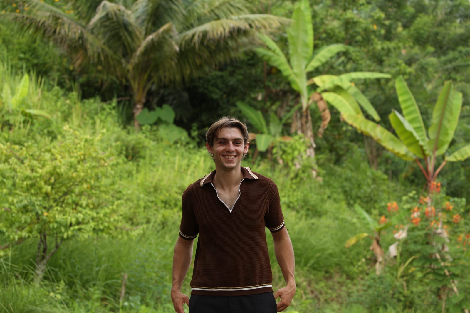 Matteo smiling in a lush tropical landscape.