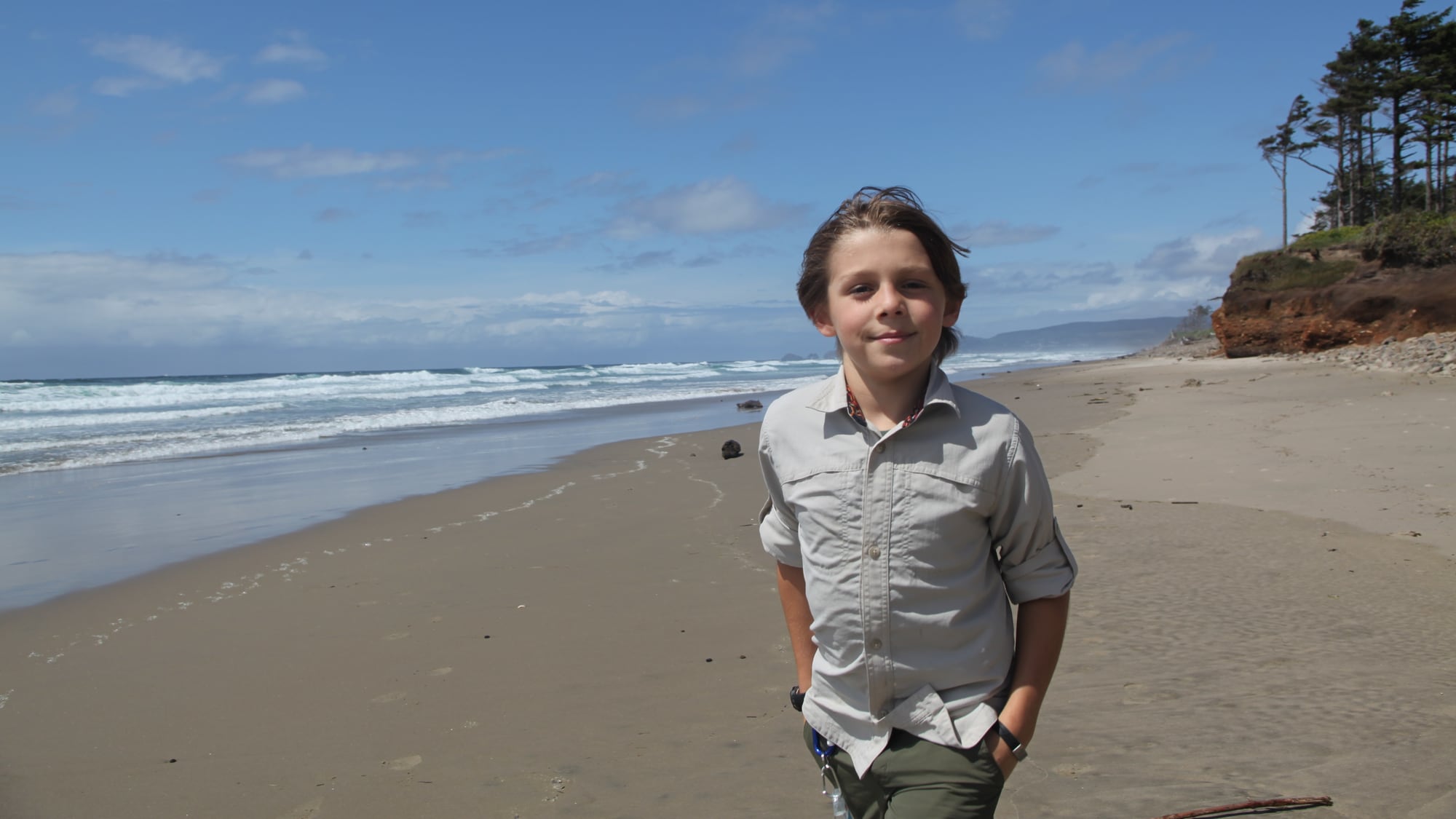 Matteo standing on a beach with cliffs and ocean behind him.