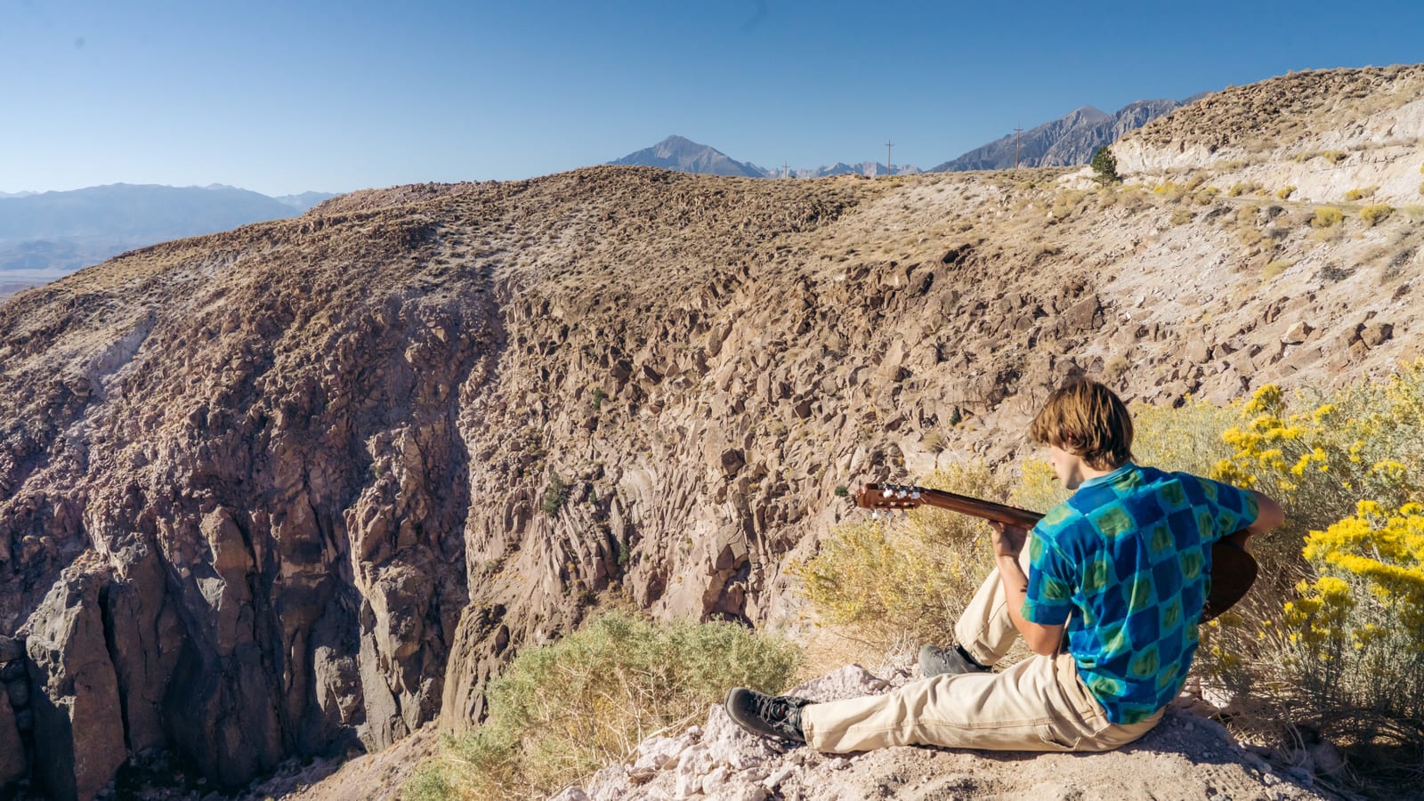 Matteo playing guitar beside a bright desert canyon.