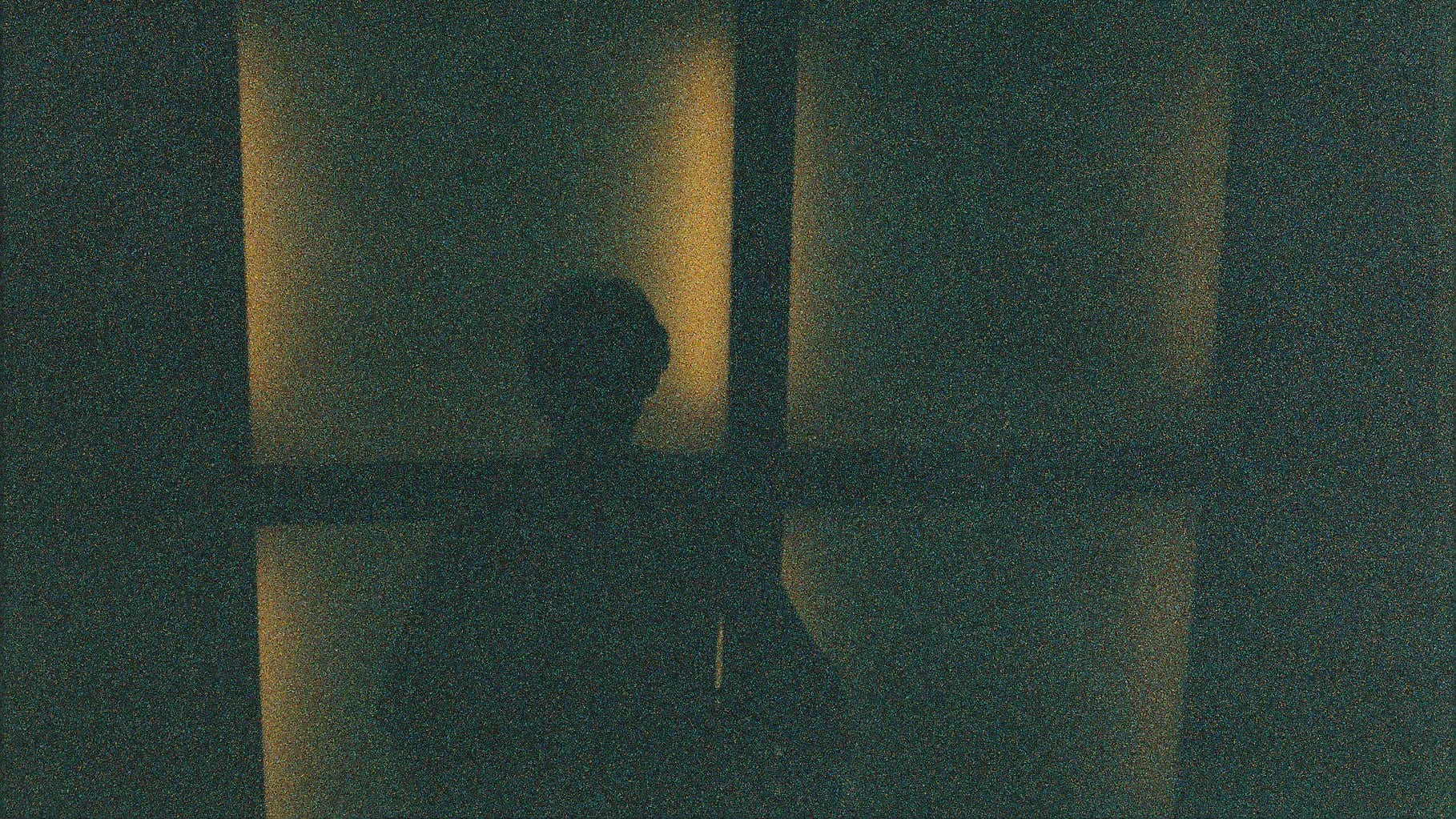 A silhouetted figure framed by warm window light.